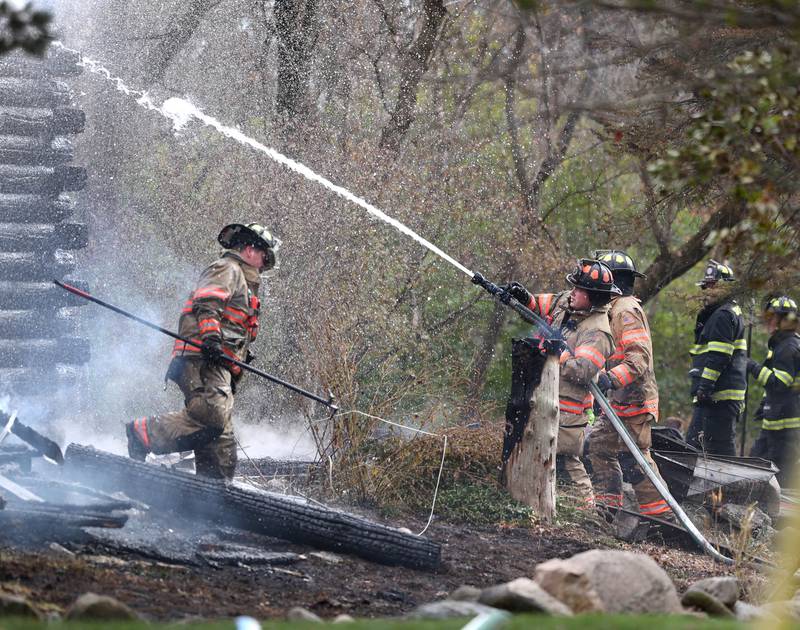 Firefighters spray water on a smoldering house that was destroyed by fire Thursday, Nov. 13, 2025, near Shabbona Grove Road in Shabbona. Several local departments responded to the general alarm structure fire.