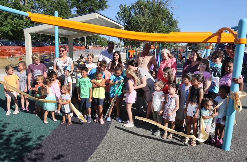 Kids cut the ribbon Friday, June 14, 2024, at the new playground at Hopkins Park. The park district was hosting a Dedication Celebration event at the park for the grand opening of the new playground and racquet courts.