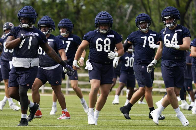 Chicago Bears offensive line Julien Davenport (74), offensive line Doug Kramer (68) and offensive line (64) Michael Schofield warm up with teammates at the team's training camp, Thursday, July 28, 2022, in Lake Forest.