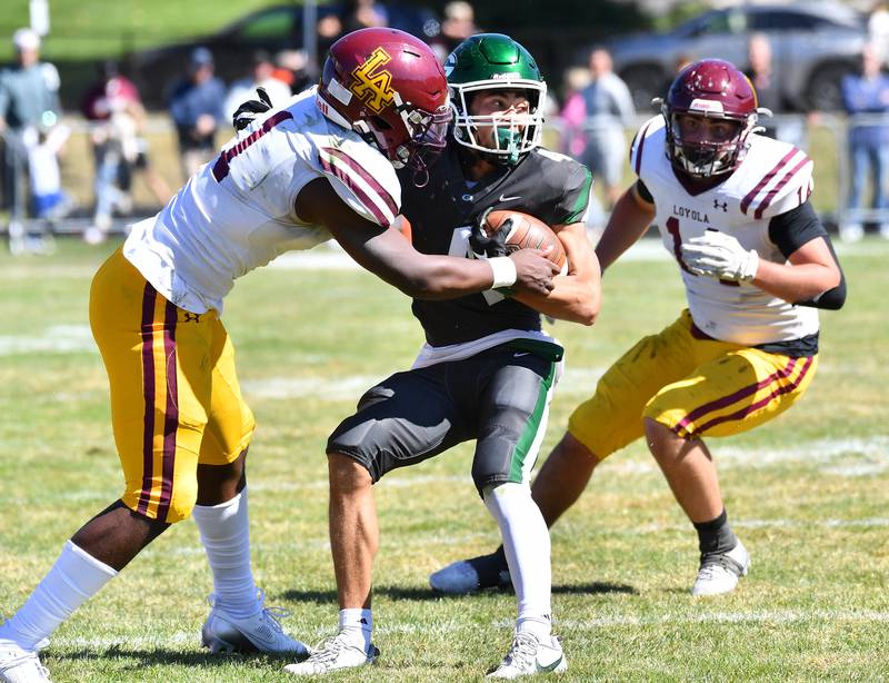 Glenbard West's Mason Ellens (middle) tries to break the tackle of Loyola's Donovan Robinson (1) during a September game at Glenbard West High School in Glen Ellyn.