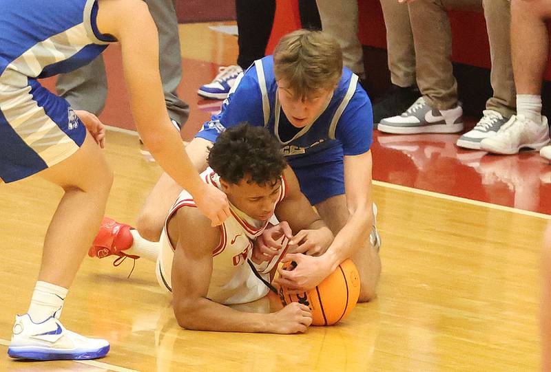 Ottawa's Hezekiah Joachim covers up a loose ball as Princeton's Jackson Mason puts a hand on the ball during the Dean Riley Shootin' The Rock Thanksgiving Tournament on Monday Nov. 24, 2025 in Kingman Gymnasium at Ottawa High School.