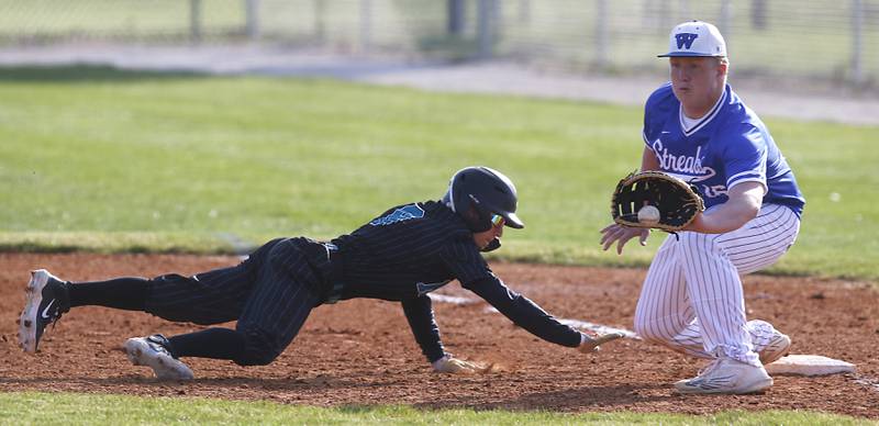 Woodstock North’s Sean Pigliacelli dives back to first base in front of the throw to Woodstock’s Everett Flannery during a Kishwaukee River Conference baseball game Tuesday, April 18, 2023, at Emricson Park.
