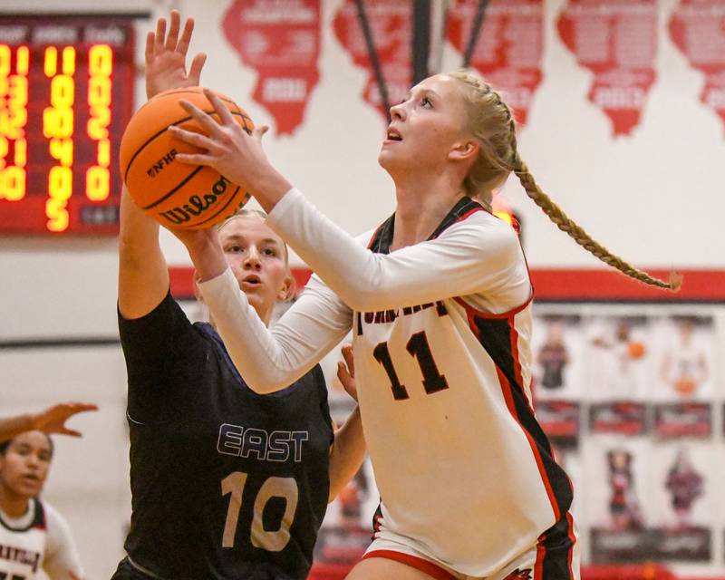 Yorkville's Aubrey Spychalski (11) goes up for a layup while being defended by Oswego East's Samantha Herrick (10) during the game on Thursday Dec. 18, 2025, held at Yorkville High School.