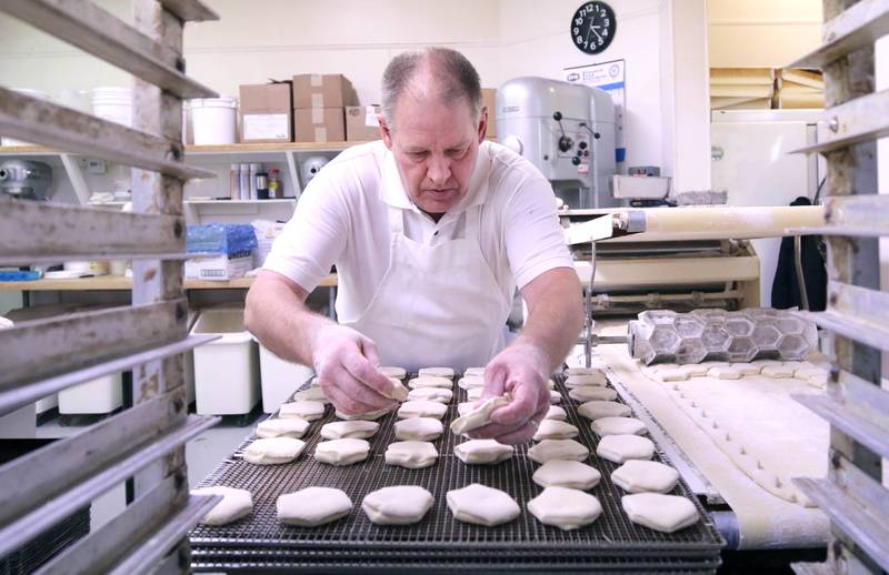 Ken Elleson, owner of Elleson's Bakery, places the sliced paczki dough on screens for frying Monday, Feb. 28, 2022, in the kitchen of the bakery in Sycamore. Elleson and members of his family will be working all night making the paczkis from scratch to be ready at 5 a.m. tomorrow for Fat Tuesday.