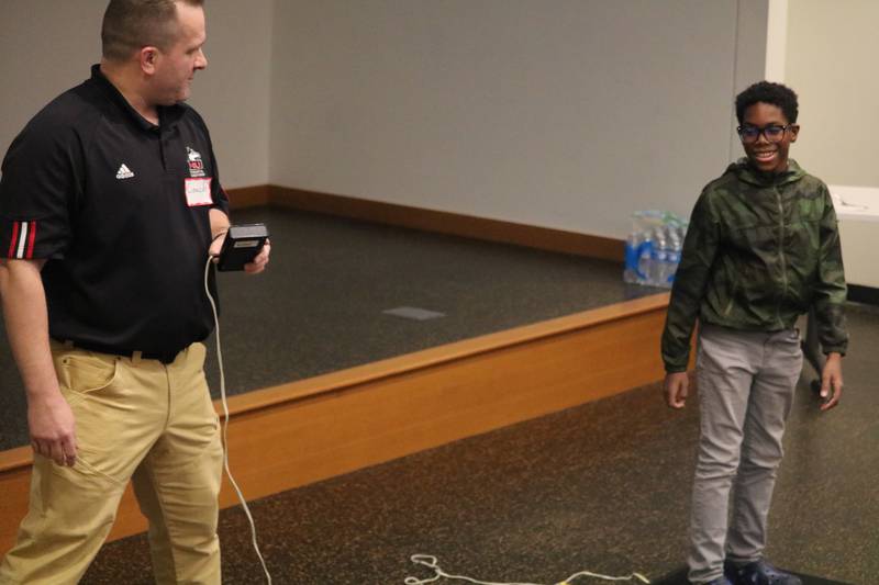 NIU instructor Brandon Male (left) leads a demonstration with assistance from Damien Nicholson, 12, on how to use a jump mat during the Teens and Family  STEM Cafe, put on Jan. 12 at the DeKalb Public Library.