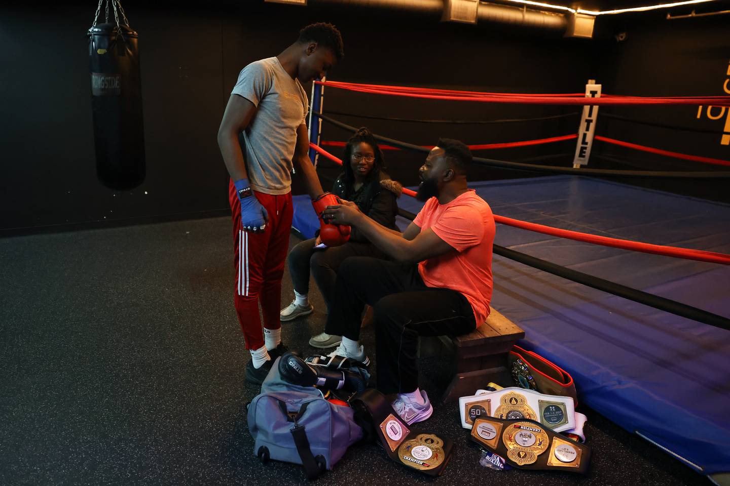 Joseph “Jojo” Awinongya, 15 years-old, his his father Joseph put on his gloves while his mother Valerie Ayertey watches at Chicago Sports & Fitness on Tuesday, February 14th.