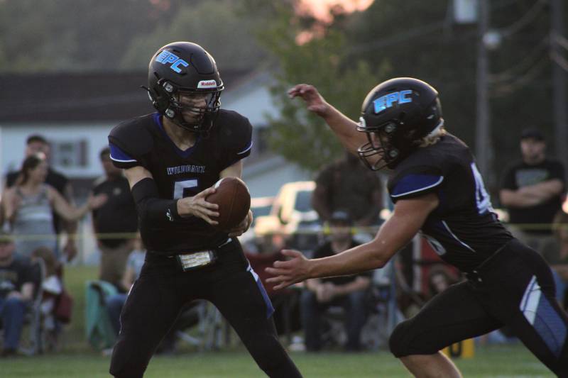 Eastland Pearl City's Kellen Henze hands off to Maddux Hayden in the first quarter of a high school football game in Lanark on Friday, Aug. 27, 2021.
