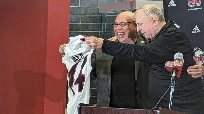 NIU athletic director Sean Frazier (left) presents Bill Baker, play-by-play broadcaster for Huskies athletics, with a jersey at media day on Tuesday, August 15. The school announced this season, Baker's 44th, will be his last.