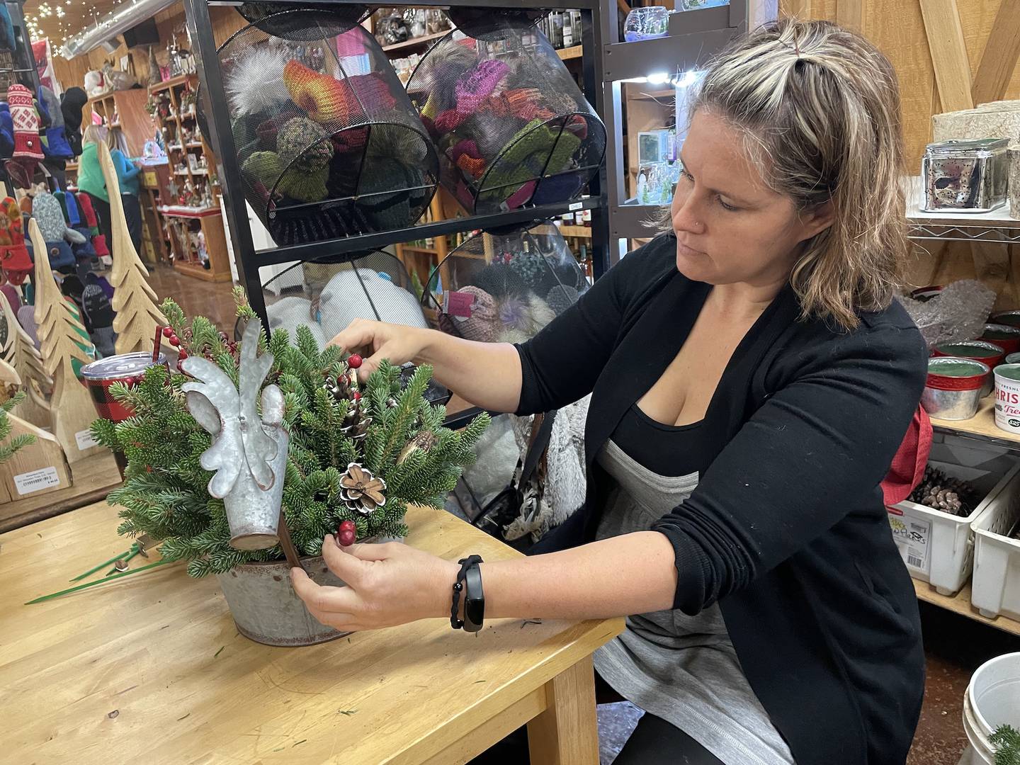 Colleen Funk adds flair in November 2025 to one of the many fresh evergreen centerpieces available for purchase at Richardson Christmas Tree Farm in Spring Grove.