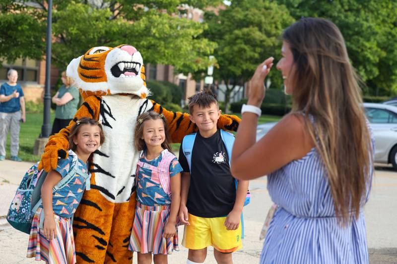Katie Tutt lets out an emotional laugh as her children, Rhett, 8, right, and twin daughters Collins, left, and Hattie, 7, pose for a photo with the Tigers mascot as they arrived for their first day of school at Herscher Intermediate School on Tuesday, Aug. 19, 2025.