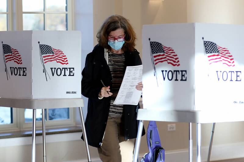 Noreen Garmisch of Crystal Lake delivers her completed ballot to the ballot collection machine at Main Beach on Tuesday, Nov. 3, 2020 in Crystal Lake.