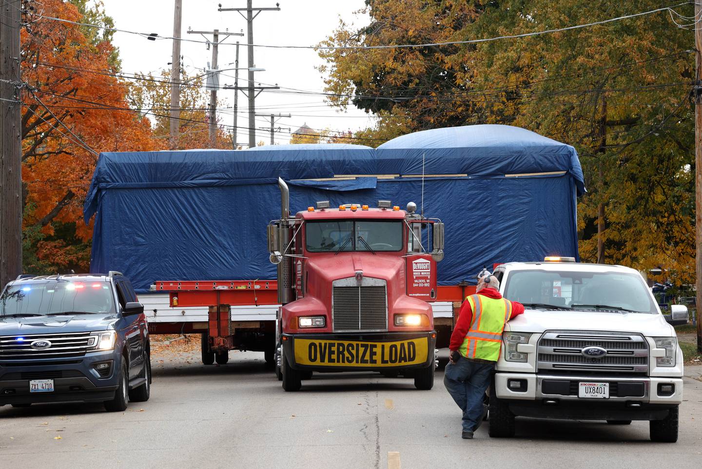 A house has to make a brief stop so a car can be moved out of the way Tuesday, Oct. 22, 2024, as it makes its way down Pleasant Street in DeKalb. The home was moved from the DeKalb County History Center property in Sycamore to its new location on Pleasant Street by Devooght House Movers and Habitat For Humanity for Heaven Allen and her son who will be living in the home when it is completed.