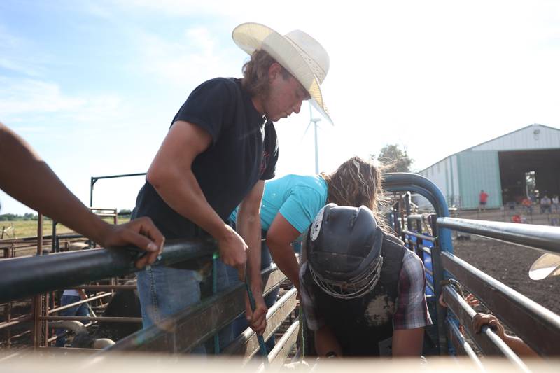 Dominic Dubberstine-Ellerbrock, left, helps a bull rider secure his rein. Dominic will be competing in the 2022 National High School Finals Rodeo Bull Riding event on July 17th through the 23rd in Wyoming. Thursday, June 30, 2022 in Grand Ridge.