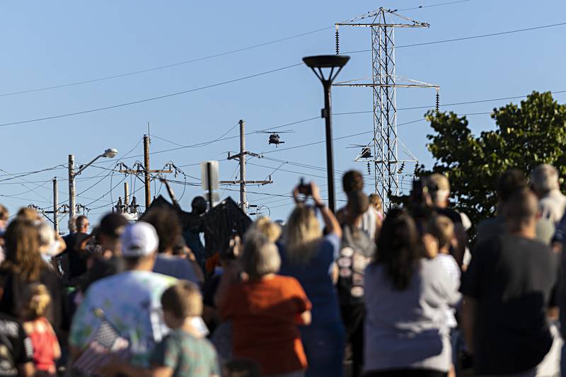 Attendees to the Vietnam Traveling Memorial Wall opening ceremony turn to watch as a pair of Blackhawk helicopters fly over RB&W Park in Rock Falls Friday, Sept. 1, 2023.