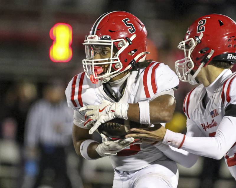 Yorkville's T.J. Harland (5) takes the handoff from Jack Beetham (2) during football game between Yorkville at Bolingbrook Friday, Oct 24, 2025 in Bolingbrook.