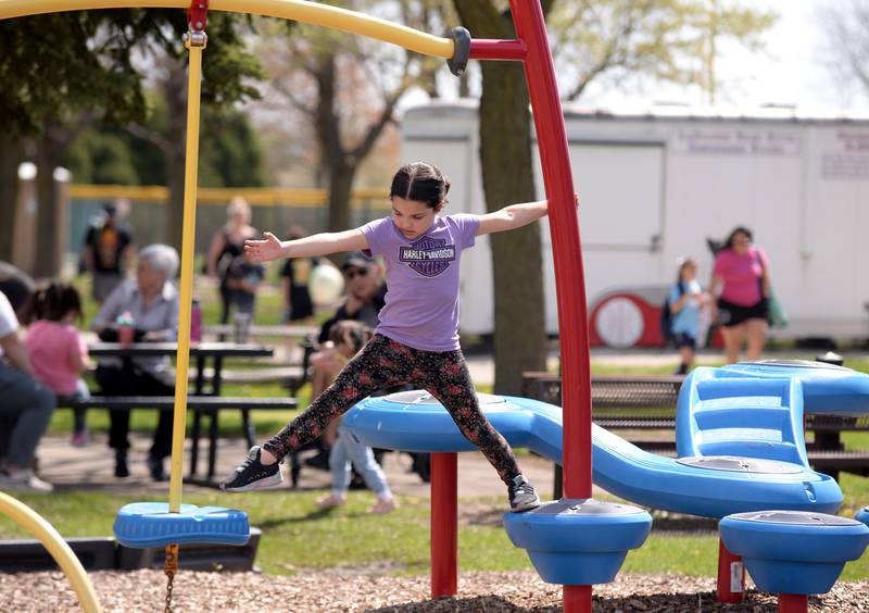 Evelyn Schorn of Brookfield tests her balance and stretches skills while playing at Sedgwick Park Sunday, April 14, 2024.