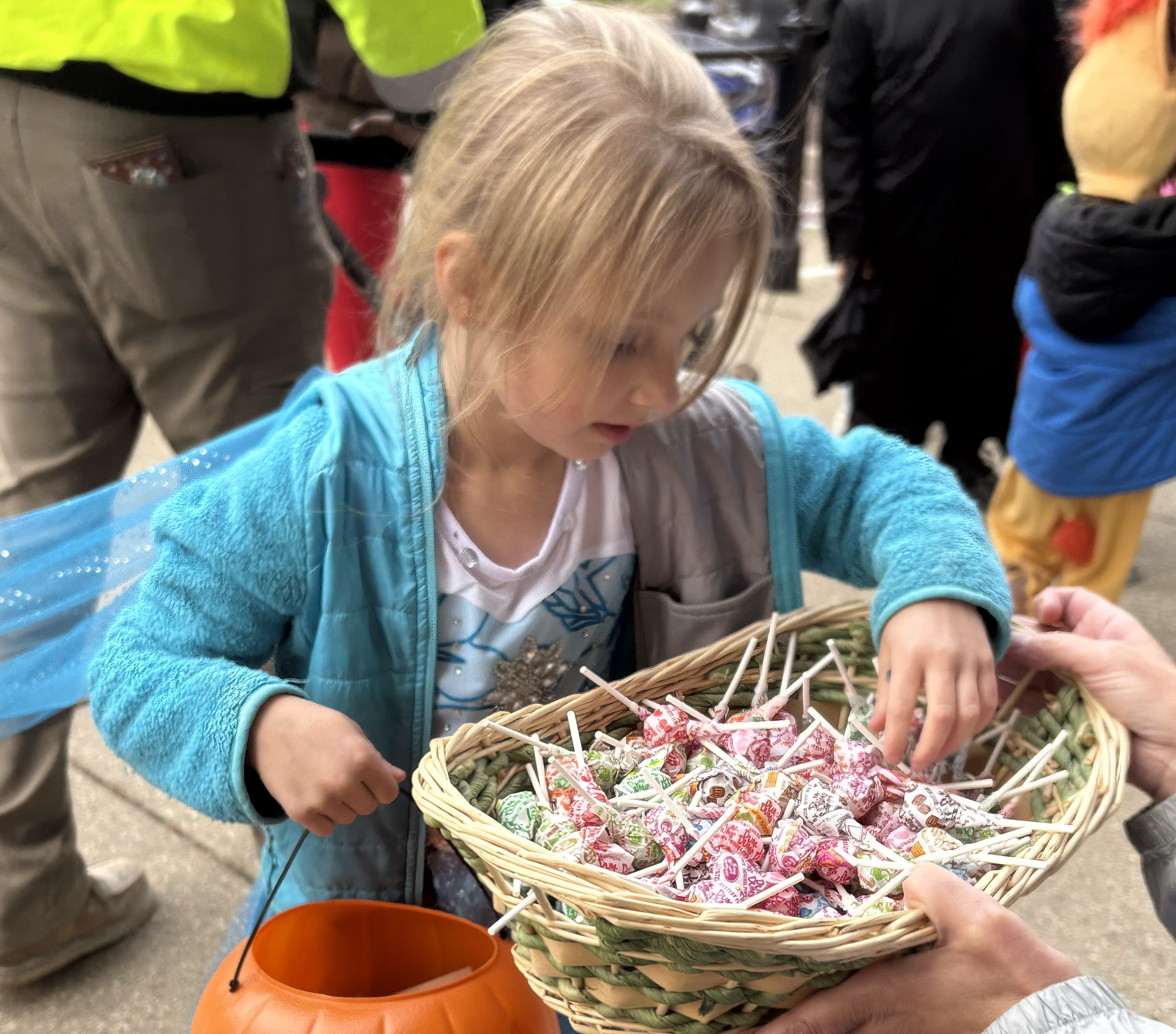 Kayleigh Prudhomme, 5, of Woodstock grabs a piece of candy at Anime and Things during Halloween on the Square in Woodstock Oct. 31, 2025.