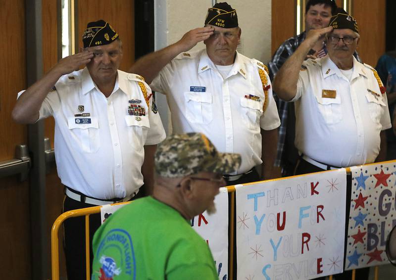 Color Guard members Lee Lexow, American Legion McHenry Post 491, Bud Whittenhall, and Rich Peters, Veterans of Foreign Wars Post 4600, salute a fellow veteran as he returns from an Honor Flight trip to Washington D.C., on Sunday, Aug. 27, 2023.