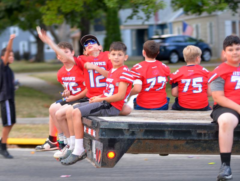 A member of a youth tackle team tosses a piece of candy to specators as his team rides in the Oregon High School homecoming parade on Wednesday, Sept. 18, 2024.