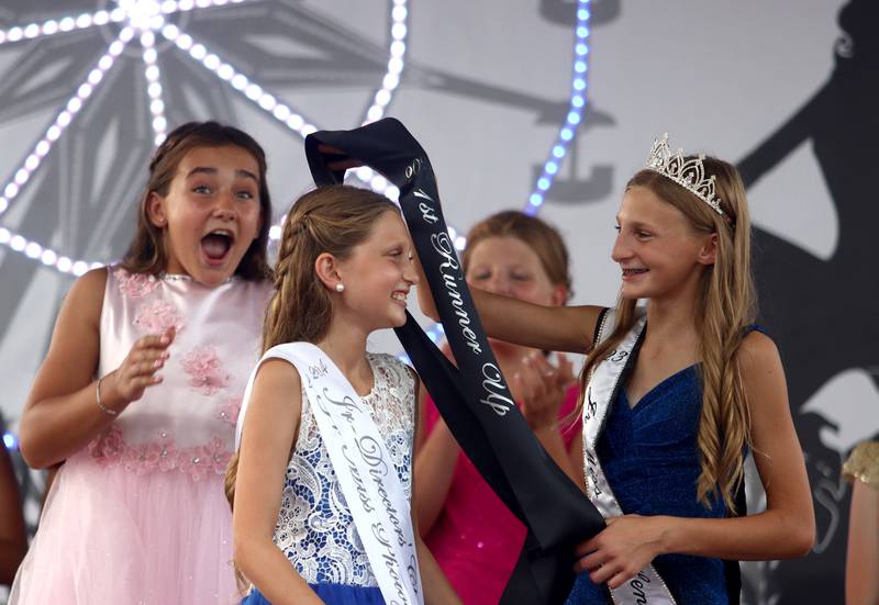 Tinley Nulle of Harvard, left, reacts after winning the Junior Miss McHenry County title at the McHenry County Fair in Woodstock on Tuesday, July 30, 2024. First runner-up Piper Crone of Harvard, center, receives her sash from outgoing Junior Miss Lou Lou Splendoria of Wonder Lake.