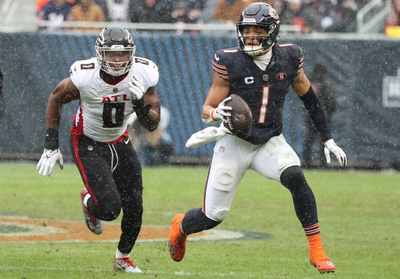 Chicago Bears quarterback Justin Fields runs escapes the pass rush of Atlanta Falcons linebacker Lorenzo Carter during their game Sunday, Dec. 31, 2023, at Soldier Field in Chicago.