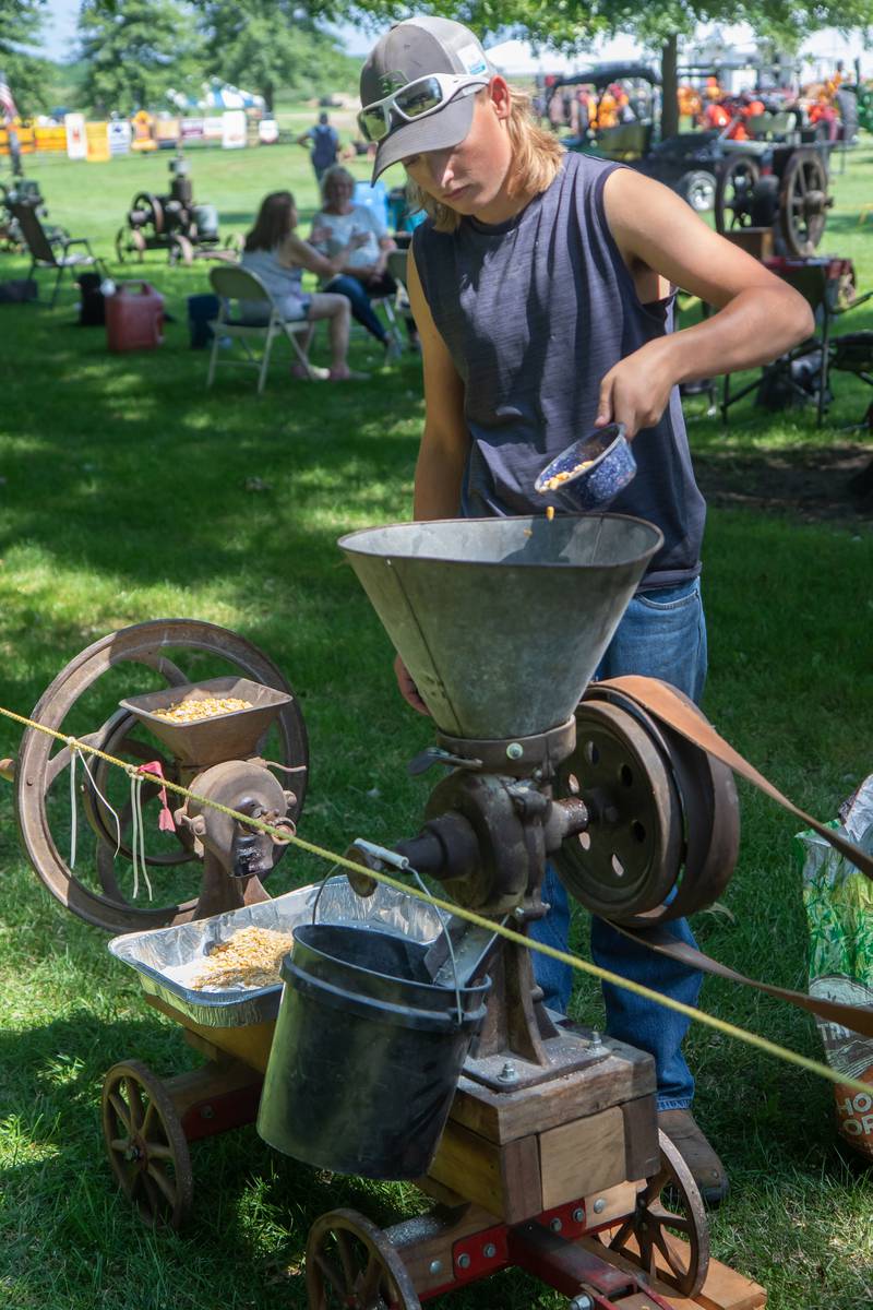 Aiden Kent-Tucker, 15, of Mendota grinds corn with the help of an antique gas engine at the at the Living History Antique Equipment Association show in Franklin Grove.