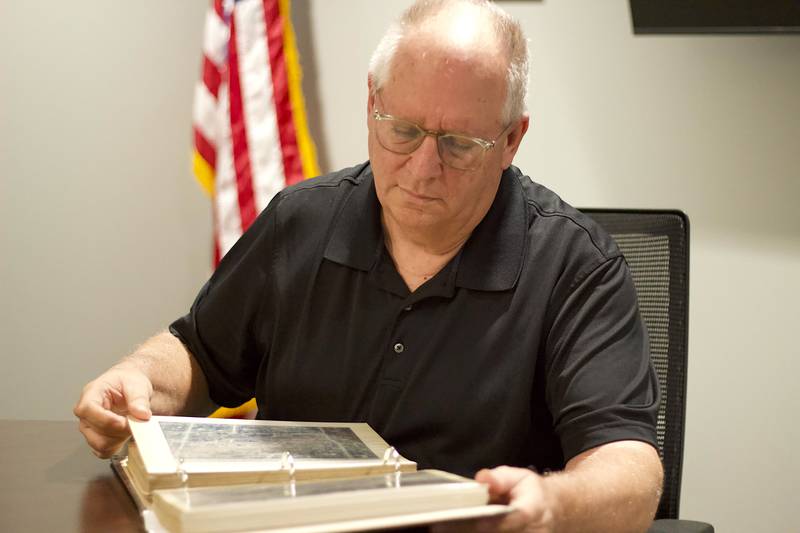 Retired Beecher Deputy Fire Chief Jerry Conner flipping through the album with photos and articles on the 1990 tornado in Plainfield while sitting in a conference room at Beecher Fire Protection District, 711 Penfield St., on Aug. 18, 2025.