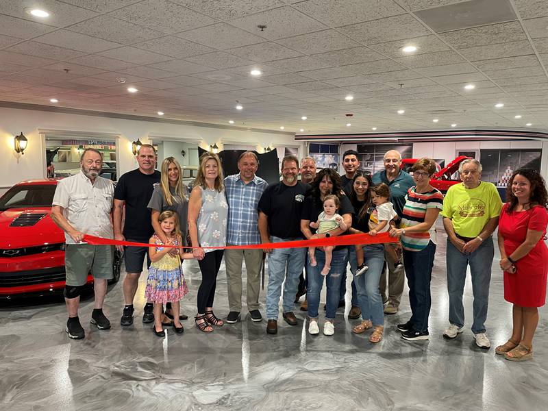 The Channahon Minooka Chamber and the Village of Minooka welcomed a new business to Minooka Sept. 14 with a ribbon cutting celebration for Aces Classic Cars. Owner Matt Ewert (center) along with family, friends, village officials (including Mayor Ric Offerman left end) and chamber officials (Chamber President & CEO Christina Van Yperen right end) are pictured together right before the ribbon cutting ceremony.