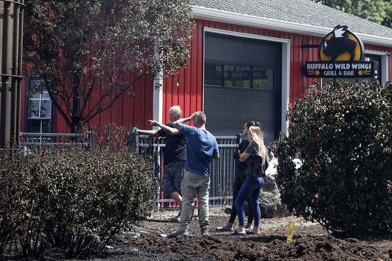 People look over the remains of barn in the 1600 block of South Rose Farm near Woodstock, after a fire leveled the building on Monday, June 1, 2024.