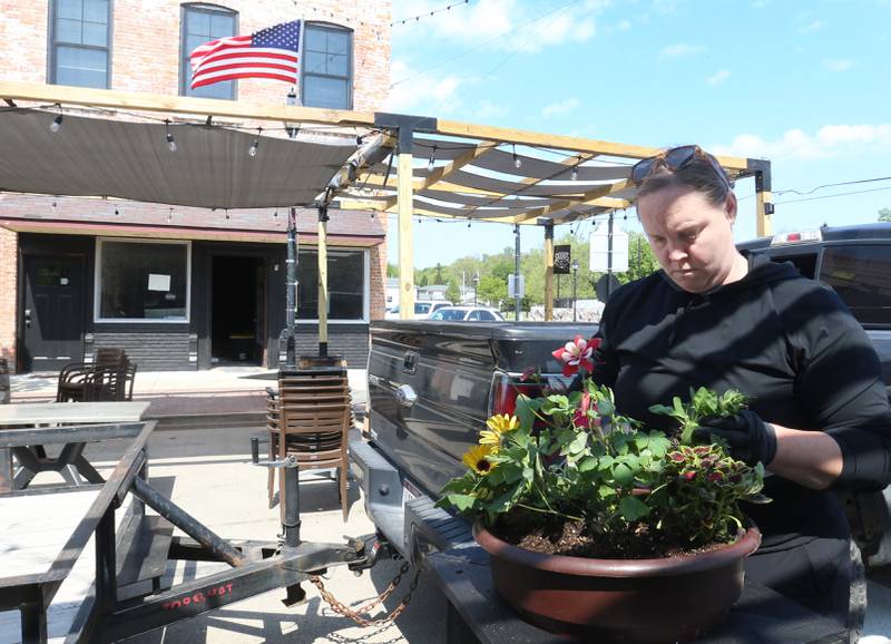 Kelsey Brannan of Country Kids Farm Market, arranges flowers in a pot on Thursday, May 8, 2025 along Mill Street downtown Utica. Utica businesses kicked off the outdoor dining season by setting up patio furniture, flowers, decorations and canopies. The outdoor dining season on Mill Street runs through October.