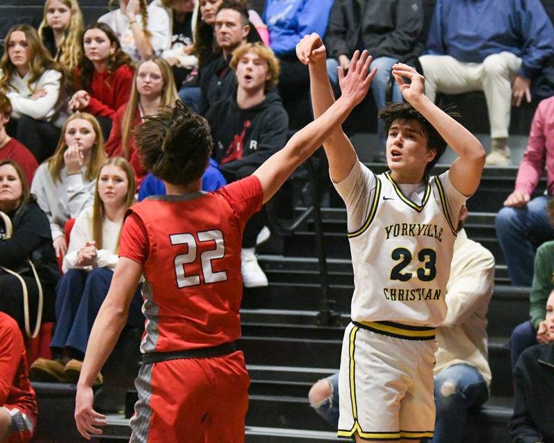 Yorkville Christian's Zach Marini (23) make a three-point basket during the game while being defended by Aurora Christian's Jacob Baumann (22) on Friday Feb. 28, 2025, held at Indian Creek High School.