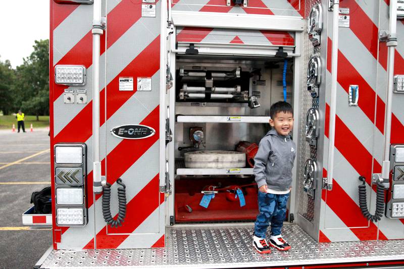 Tae Jo, 3, of Batavia stands on the back of a Kaneville Fire Department engine duirng the Kane County Sheriff’s National Night Out in St. Charles on Tuesday, Aug. 6, 2024.