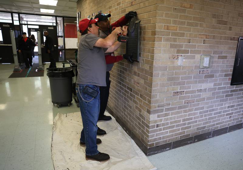 Randy Williams, foreground, and Anthony Brown Sr. remove a plaque where they believe a time capsule was place at Grompers Junior High School on Wednesday, May 1, 2026 in Joliet. In 1969 students placed items in a time capsule and sealed it inside a wall when an extension was built at Grompers Junior High School.