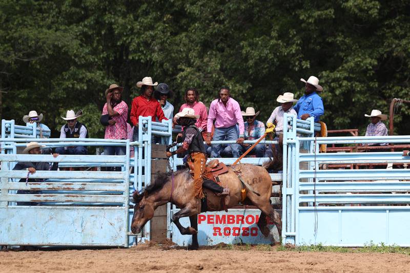 Fellow contestants watch as Jose Pedraza, of Madison, Wisc., enters the arena to compete in bronc riding during the 50th Pembroke Rodeo on Sunday, May 24, 2026.