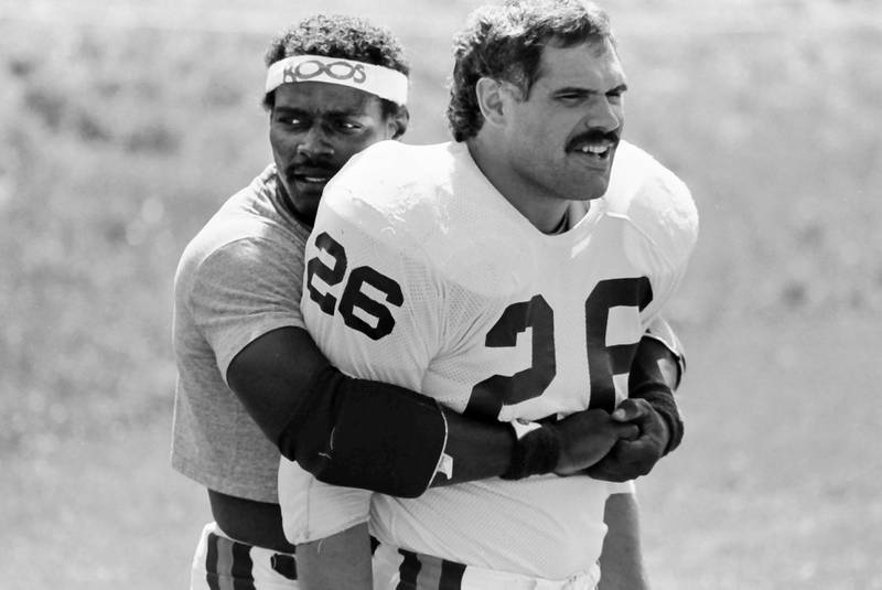 Chicago Bears running back Walter Payton hugs fulback Matt Suhey during training camp on Wednesday, June 12, 1985 in Platteville Wis.