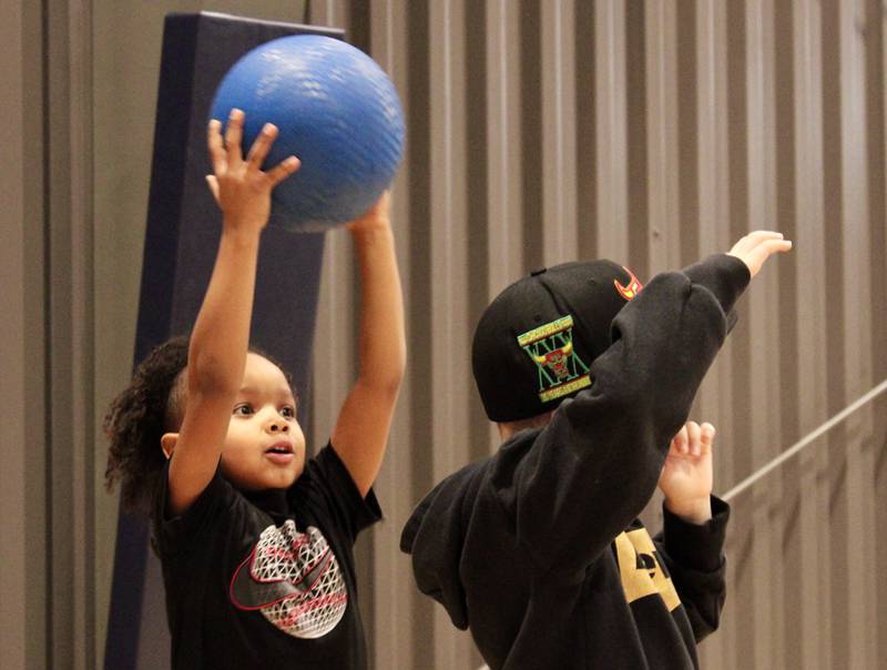 Ezekiel Robinson prepares to hand off a playground ball to Zayvin Schultheis as part of the over-under relay game on Tuesday morning as part of the Winter Mini Spark day camp at The Facility in Dixon.