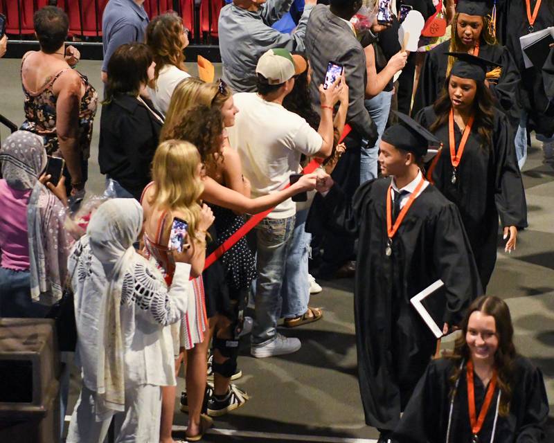 A St. Charles East graduate gets a fist bump as he walks out of the Convocation center in DeKalb after the commencement ceremony on Monday May 18, 2026.