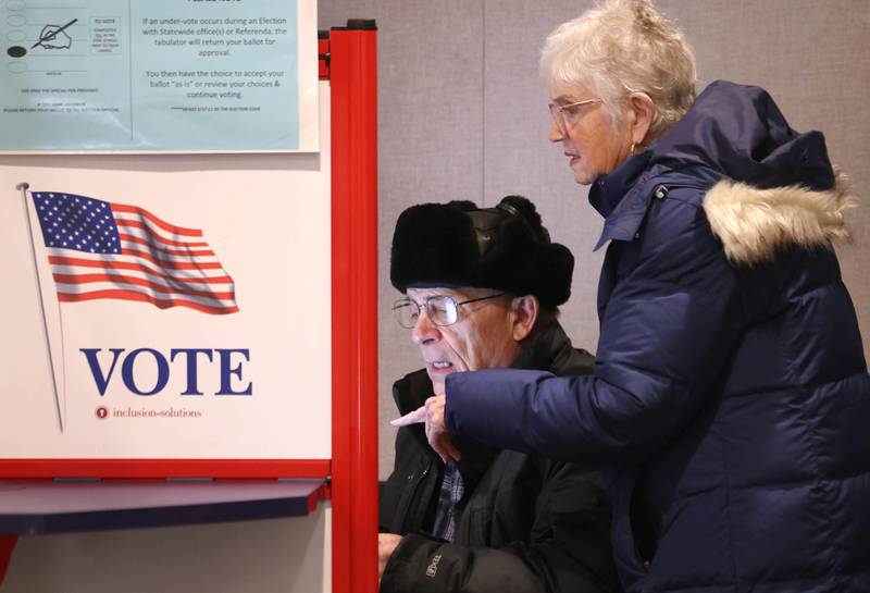 Richard Dowen, from DeKalb, gets some help using the touchscreen voting machine from his wife Peggy as he casts his ballot in the primary election Tuesday, March 17, 2026, at the DeKalb County Administration Building in Sycamore.
