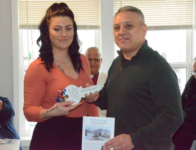 New Fox Valley Habitat homeowner Jenna Strohmenger receives a ceremonial house key from Aurora deputy mayor Guillermo Trujillo at dedication ceremonies Saturday, March 11, for her home at 654 Spruce St. in Aurora. Strohmenger and daughters Aniya, 8; Adrianna, 14; and Avianna, 1, moved in Saturday afternoon.