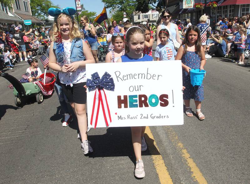 Reagan Komstock, 8, of Wauconda, walks with Mrs. Ross' second grade class as she holds up a sign to "Remember Our Heroes!" Monday, May 29, 2023, on Main Street during the Wauconda Memorial Day Parade.