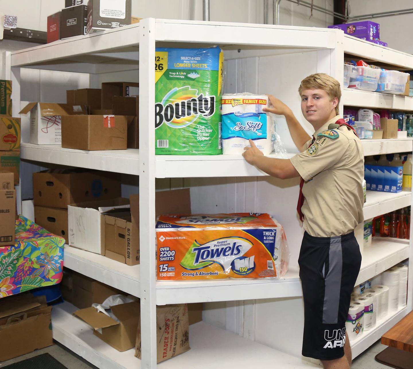 Billy Eby stocks toilet paper and paper towels on shelves he built as his Eagle Scout Project at Between Friends Food Pantry of Sugar Grove on Wednesday, June 8, 2022.