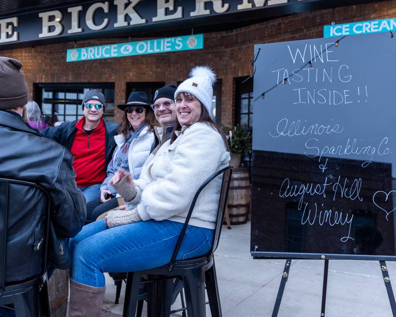 Friends enjoy wine gathered around table at the wine walk on Feb. 14, 2026 on Mill Street in Utica.