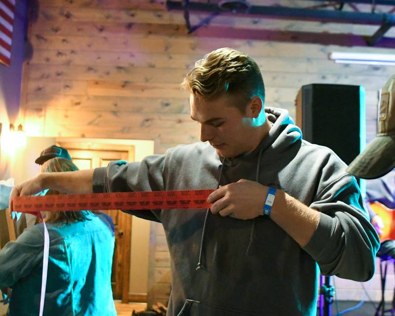 Firefighter Joseph Batusich rolls out an arm length of tickets for the raffle prizes on Wednesday Nov. 27, 2024, at Fatty's Pub and Grille in DeKalb during the DeKalb Fire Fighters Local 1236 union's Tip A Firefighter event to fundraise for the Muscular Dystrophy Association.