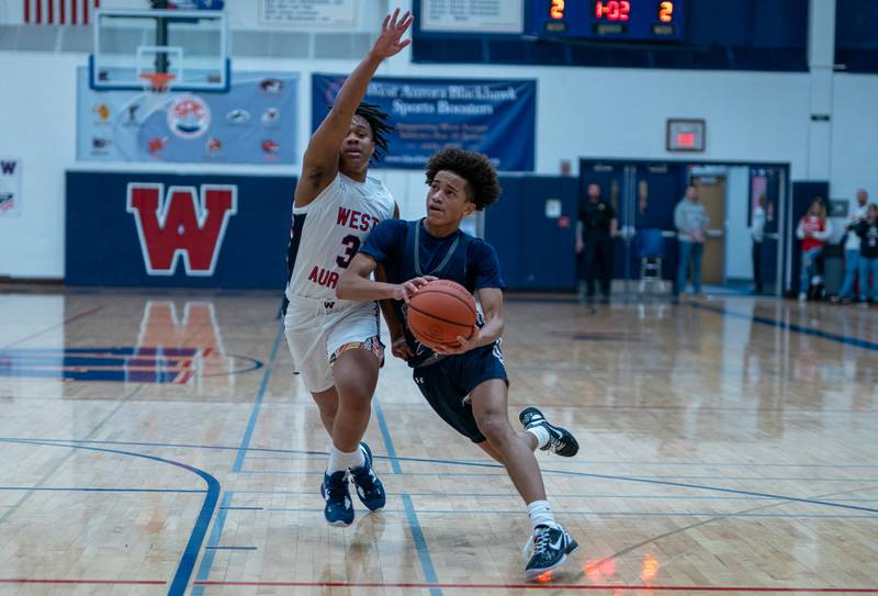 Oswego East's Bryce Shoto (2) drives to the basket against West Aurora's Datavion McClain (3) during a basketball game at West Aurora High School on Friday, Jan 27, 2023.