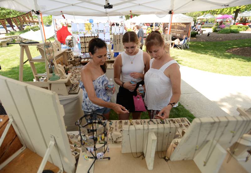 (Left to right) Judy Hollowed of LaGrange Park, and Olivia and Janet Berley of Hinsdale look over the jewelry made by artist Laura Nolan of Naperville during the Hinsdale 4th of July Family Festival Tuesday June 4, 2023.