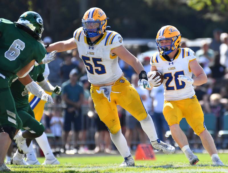 Lyons Township’s EJ Kuhlman runs behind blocking by Roman Sosnovyy (55) during a game against Glenbard West on September 27, 2025 at Glenbard West High School in Glen Ellyn.