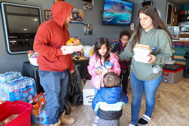 Sarah Brandenburg, right, and her family, all of Aroma Park, pick up meals at the Fun Hub on March 12, 2026, as the small bar transformed into a bustling hub of supplies, food and resources following the March 10 tornado. Brandenburg said their home sustained a lot of damage and the meals were a big help. "It shows how much everyone is coming together," she said.