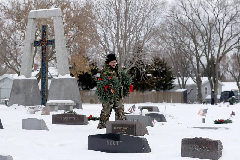 Bonnie Hazelwood looks for a veteran’s gravesite while laying wreaths during McHenry's Wreath Laying Ceremony in honor of fallen veterans on Friday, Dec. 5, 2025, at St. Mary's Catholic Cemetery in McHenry. The event was hosted by McHenry American Legion Post 491 and Team Home Depot.