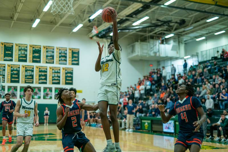 Waubonsie Valley's Tyreek Coleman (12) shoots the ball in the post against Oswego’s Armani Hunter (2) and Jayden Riley (4) during a Waubonsie Valley 4A regional semifinal basketball game at Waubonsie Valley High School in St.Charles on Wednesday, Feb 22, 2023.