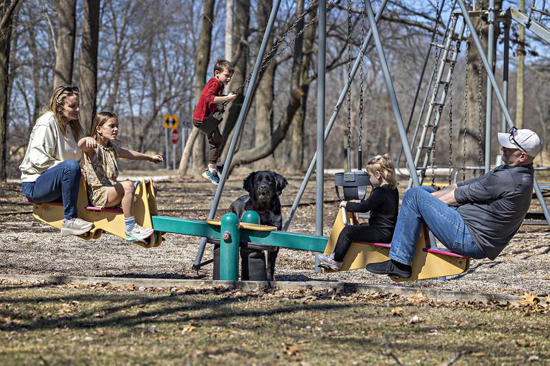 Family members Tonja Clark (left), Raleigh Partridge, 9, Jamie Harrison, 3, and Bill Clark enjoy the ups and downs of a teeter totter as pooch Sadie watches and Sean Partridge, 7, swings Saturday, March 21, 2026, at Franklin Creek State Park.